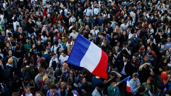 People hold French flags as they gather at the Place de la Republique after partial results in the second round of the early French parliamentary elections, in Paris, France(REUTERS)