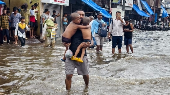 A man carries two children in Chunabhatti's Swadeshi Mill Chawl, flooded by last night's rains. HT Photo Raju Shinde 