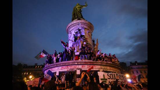 Participants wave French national tricolors during an election night rally following the first results of the second round of France's legislative election at Place de la Republique in Paris on July 7, 2024. (Photo by Emmanuel Dunand / AFP) (AFP)