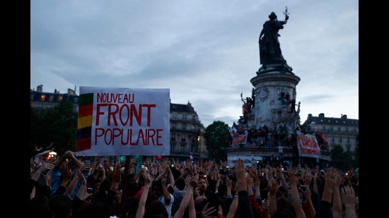 People raise their arms and hands as they gather at the Place de la Republique after partial results in the second round of the early French parliamentary elections, in Paris, France, July 7, 2024. The slogan reads 