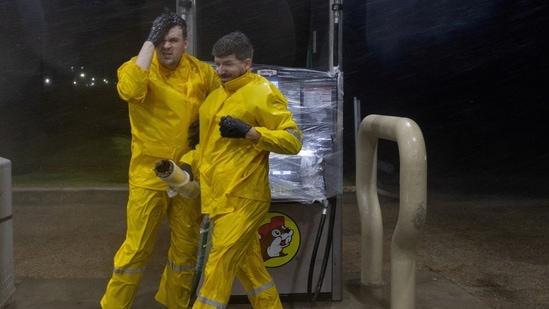 Blake Charanza covers his face from the piercing rain due to Hurricane Beryl, after he and Shawn Trent covered a fuel pump with plastic at Buc-ee's, in Freeport, Texas, U.S., July 8, 2024.  REUTERS/Adrees Latif     TPX IMAGES OF THE DAY