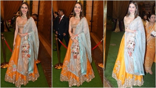 Manushi Chhillar attended the Haldi function in a blue and orange-hued lehenga set featuring an embellished bralette, a Resham embroidered A-line lehenga, and an organza dupatta. She paired the ensemble with a choker necklace, rings, earrings, an embellished potli bag, berry-toned lips, centre-parted loose tresses, and kohl-lined eyes. (Instagram)