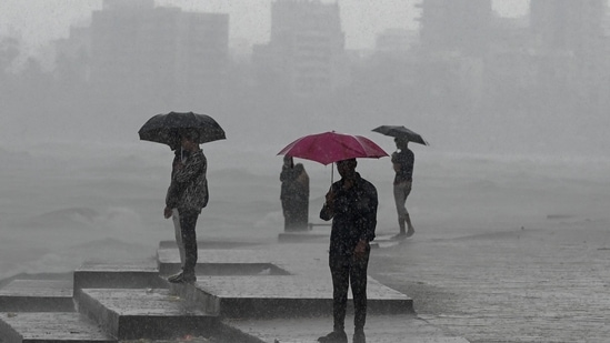 TOPSHOT - People enjoy rain showers near the sea front in Mumbai on July 8, 2024. (Photo by Punit PARANJPE / AFP)(AFP)