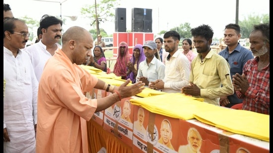 UP chief minister Yogi Adityanath distributing relief kits to flood hit people at Sharda barrage in Kheri on Wednesday. (HT Photo)