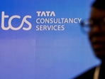 A man walks past a logo of Tata Consultancy Services (TCS) before a press conference.