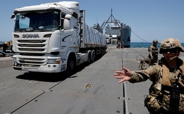 As bombs thunder in Gaza, just across the border in southern Israel truck driver Itzik waits in a barbed-wire protected parking lot for his delivery to clear inspection into the hunger-stricken territory. (Reuters ( relevant image ) )