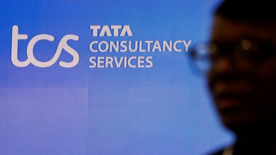 A man walks past a logo of Tata Consultancy Services (TCS) before a press conference.(Reuters)