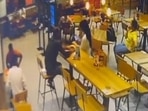 Footage of the incident shows the shooters seated behind the victim, who is sitting across the woman, at a long table. (HT) Footage of the incident shows the shooters seated behind the victim, who is sitting across the woman, at a long table. (HT)