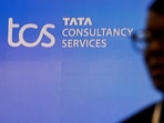 TCS share price: A man walks past a logo of Tata Consultancy Services (TCS) before a press conference.