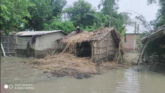 A villager in Phoolbehar repairing his thatched roof in a flooded village on Friday. (HT Photo)