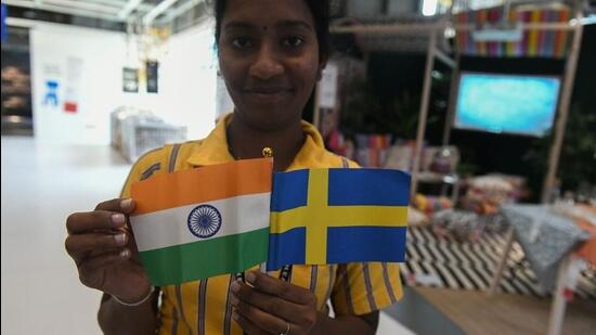 An Indian worker holds flags of India and Sweden. (Photo by NOAH SEELAM / AFP) (AFP)