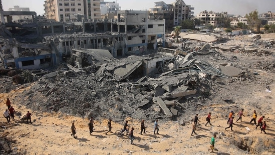 People walk on rubble at the damaged UN Relief and Works Agency for Palestine Refugees (UNRWA) building complex in western Gaza City's Al-Sinaa neighbouhood on July 12, 2024.(AFP)