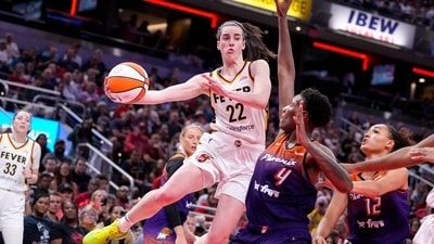 Indiana Fever guard Caitlin Clark (22) makes a pass over Phoenix Mercury forward Natasha Mack (4) in the second half of a WNBA basketball game in Indianapolis, Friday, July 12, 2024. (AP/Michael Conroy) Indiana Fever guard Caitlin Clark (22) makes a pass over Phoenix Mercury forward Natasha Mack (4) in the second half of a WNBA basketball game in Indianapolis, Friday, July 12, 2024. (AP/Michael Conroy)