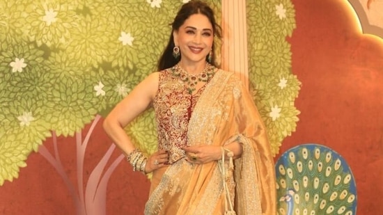 Madhuri Dixit Nene was one of the early guests at Anant Ambani and Radhika Merchant's wedding day 2 and stole the limelight in a golden saree contrasted with a sultry sleeveless maroon blouse. (HT Photo)