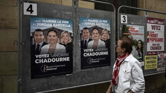 A woman looks at election posters of French far-right Rassemblement National (RN) candidate Sandrine Chadournec (C) in Libourne, southwestern France on July 2, 2024 as part of the French legislative elections. (Photo by Philippe LOPEZ / AFP) (AFP)