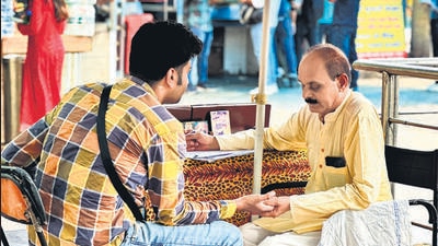Palmist Uttamji pores over a customer’s palm at his booth. (HT Photo) Palmist Uttamji pores over a customer’s palm at his booth. (HT Photo)