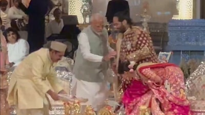 Anant Ambani and Radhika Merchant touching PM Modi's feet. Anant Ambani and Radhika Merchant touching PM Modi's feet.