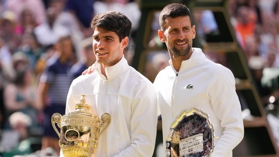Carlos Alcaraz of Spain holds his trophy as he stands with Novak Djokovic of Serbia after winning the men's singles final at the Wimbledon(AP)