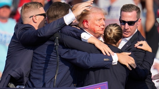 Republican presidential candidate former President Donald Trump is surrounded by U.S. Secret Service agents as he is helped off the stage at a campaign rally in Butler, Pa., Saturday, July 13, 2024. (AP Photo/Gene J. Puskar)(AP)