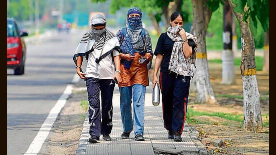 Pedestrians cover their faces to protect themselves from the sun in Ludhiana on Monday. (Manish/HT)