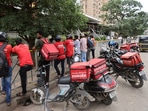 Gig workers wait in line to collect their delivery order outside a mall in Mumbai.