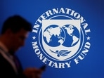 A participant stands near a logo of IMF at the International Monetary Fund - World Bank annual meeting.