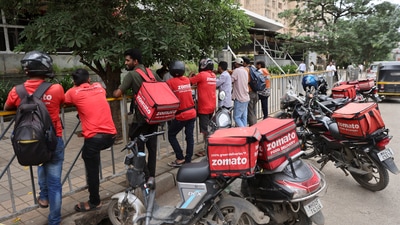 Gig workers wait in line to collect their delivery order outside a mall in Mumbai. (Reuters)