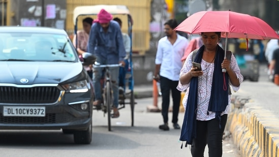 Noida, India- July 11, 2024: Due to the increase in temperature and humidity after the rain in Delhi-NCR, passengers are walking under umbrella to avoid the heat, in Noida, India, on Thursday, July 11, 2024. (Photo by Sunil Ghosh / Hindustan Times) 