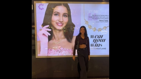 Latest news on July 17, 2024: Nancy Tyagi posing against the lightbox that has her poster. 