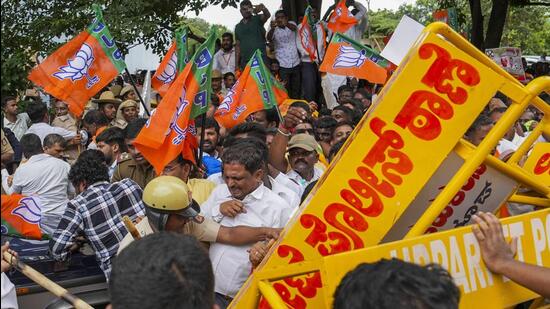 Police personnel stop BJP workers trying to climb barricades during a protest demanding the resignation of Chief Minister Siddaramaiah over the alleged scam in the Karnataka Maharshi Valmiki Scheduled Tribes Development Corporation Ltd., in Bengaluru on Thursday. (PTI)