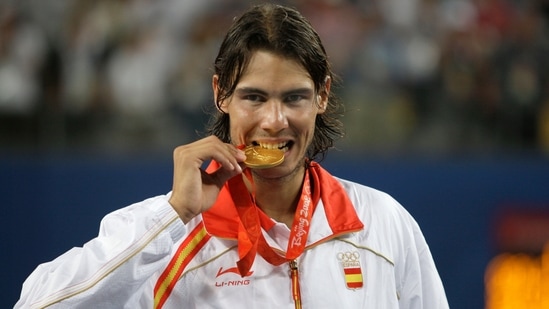 Rafael Nadal bites his gold medal for the photographers after beating Fernando Gonzalez of Chile during their Gold medal singles tennis at the Beijing 2008 Olympics.(AP)