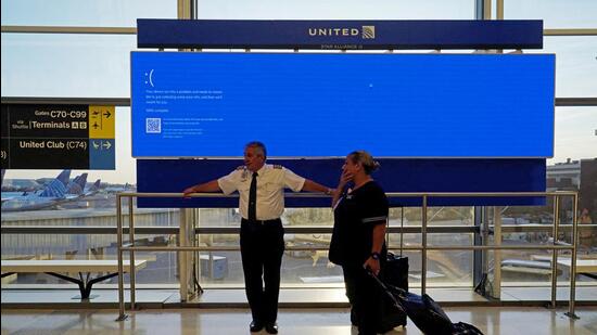 United Airlines employees wait by a departures monitor displaying a blue error screen, also known as the “Blue Screen of Death” inside Terminal C in Newark International Airport. (REUTERS)