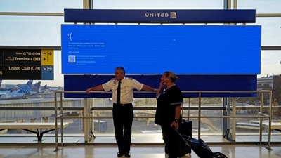 United Airlines employees wait by a departures monitor displaying a blue error screen, also known as the “Blue Screen of Death” inside Terminal C in Newark International Airport in Newark, New Jersey on July 19. (Reuters)