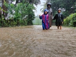 A man along with children walks through a waterlogged street during rains, in Karnataka.(PTI) A man along with children walks through a waterlogged street during rains, in Karnataka.(PTI)
