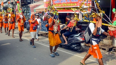 Muzaffarnagar: Kanwariyas walk past the shops on which banners with shopkeepers' name were put up on Kanwar Marg after an order issued by Uttar Pradesh Government, in Muzaffarnagar, Saturday, July 20, 2024. (PTI Photo) (PTI07_20_2024_000145A) (PTI) Muzaffarnagar: Kanwariyas walk past the shops on which banners with shopkeepers' name were put up on Kanwar Marg after an order issued by Uttar Pradesh Government, in Muzaffarnagar, Saturday, July 20, 2024. (PTI Photo) (PTI07_20_2024_000145A) (PTI)