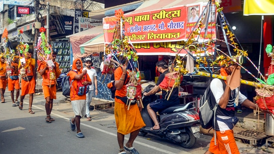 Muzaffarnagar: Kanwariyas walk past the shops on which banners with shopkeepers' names were put up on Kanwar Marg after an order issued by the Uttar Pradesh government. (PTI)