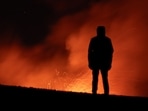 A person looks on as smoke and lava rise from a crater of Mount Etna, Europe's most active volcano in Italy July 23, 2024. Sicily travel alert: Eruption at largest active volcano in Europe, Mount Etna, forces closure of Catania airport (Photo by REUTERS/Etna Walk/Marco Restivo)