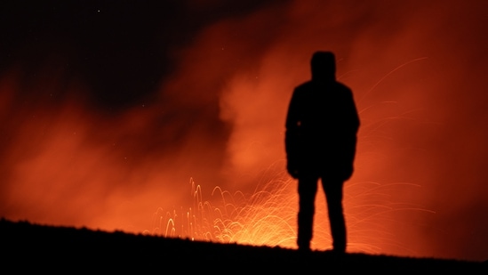 A person looks on as smoke and lava rise from a crater of Mount Etna, Europe's most active volcano in Italy July 23, 2024. Sicily travel alert: Eruption at largest active volcano in Europe, Mount Etna, forces closure of Catania airport (Photo by REUTERS/Etna Walk/Marco Restivo)
