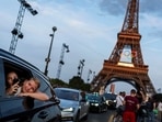 Passengers in the back of a taxi film themselves as they leave the Eiffel Tower decorated with the Olympic rings ahead of the 2024 Summer Olympics. Passengers in the back of a taxi film themselves as they leave the Eiffel Tower decorated with the Olympic rings ahead of the 2024 Summer Olympics.