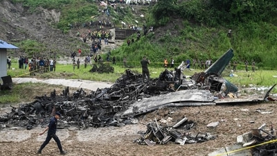 People stand at the site after a Saurya Airlines' plane crashed during takeoff at Tribhuvan International Airport in Kathmandu on July 24, 2024.  (Photo by PRAKASH MATHEMA / AFP) (AFP)