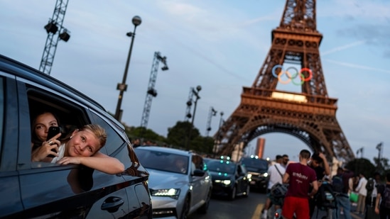 Passengers in the back of a taxi film themselves as they leave the Eiffel Tower decorated with the Olympic rings ahead of the 2024 Summer Olympics. (AP)