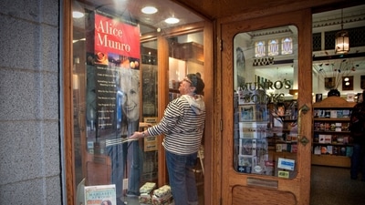 FILE PHOTO: An employee adjusts a poster of Canadian author Alice Munro in Munro's bookstore after she won the Nobel Prize for Literature in Victoria, British Columbia October 10, 2013. REUTERS/Andy Clark/File Photo (REUTERS)