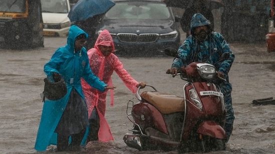 Children push their father's scooter through a flooded street as it rains in Mumbai, India, Thursday, July 25, 2024. (AP Photo/Rafiq Maqbool)(AP)