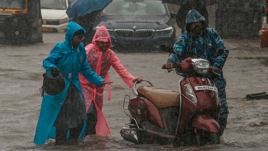 Children push their father's scooter through a flooded street as it rains in Mumbai, India, (AP Photo)