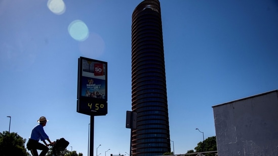 A cyclist rides towards a thermometer that reads 45 degrees Celsius on a street of Seville on July 23, 2024. July 21, 2024 was the hottest day ever registered globally, according to preliminary data published on July 23, 2024 by the EU's climate monitor. The Copernicus Climate Change Service (C3S) said the global average surface air temperature on July 21 was 17.09 degrees Celsius, a fraction above the previous record set in 2023. (Photo by CRISTINA QUICLER / AFP)(AFP)