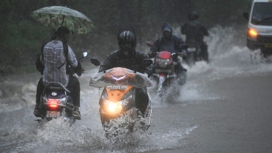 People driving through water-logged roads at Aarey colony in Mumbai. (HT Photo)