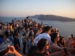 Tourists wait for the sunset in the village of Oia on the Greek island of Santorini. Like other popular tourist destinations, the Cycladic island perched on a volcano is approaching over-saturation, and now wants to restrict the number of cruise ships. (Photo by Aris Oikonomou / AFP)