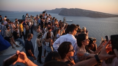 Tourists wait for the sunset in the village of Oia on the Greek island of Santorini. Like other popular tourist destinations, the Cycladic island perched on a volcano is approaching over-saturation, and now wants to restrict the number of cruise ships. (Photo by Aris Oikonomou / AFP) Tourists wait for the sunset in the village of Oia on the Greek island of Santorini. Like other popular tourist destinations, the Cycladic island perched on a volcano is approaching over-saturation, and now wants to restrict the number of cruise ships. (Photo by Aris Oikonomou / AFP)