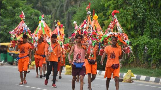 Kanwariyas carrying holy water collected from River Ganga in Haridwar going back to their hometown in Rajasthan state during the Kanwar Yatra at National Highway-48 near Signature Tower Chowk in Gurugram on Friday. (HT Photo)