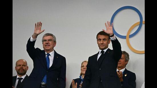 The President of the International Olympic Committee (IOC) Thomas Bach (L) and France's President Emmanuel Macron wave as they arrive to attend the opening ceremony. (AFP)